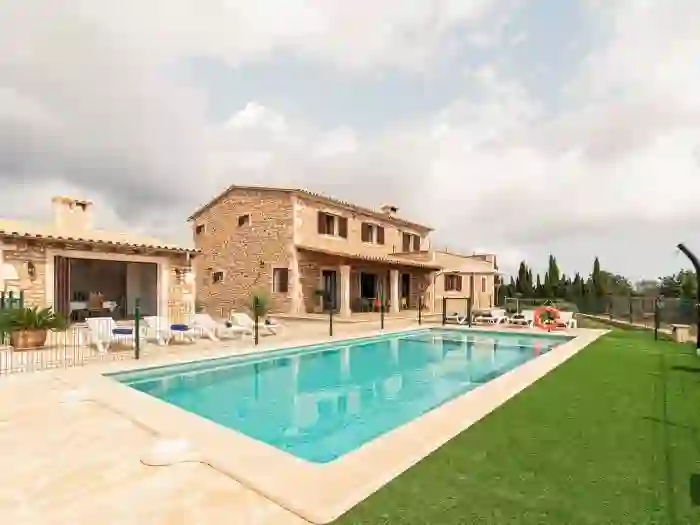 Foto original de una villa rústica de piedra con piscina y jardín mediterráneo.